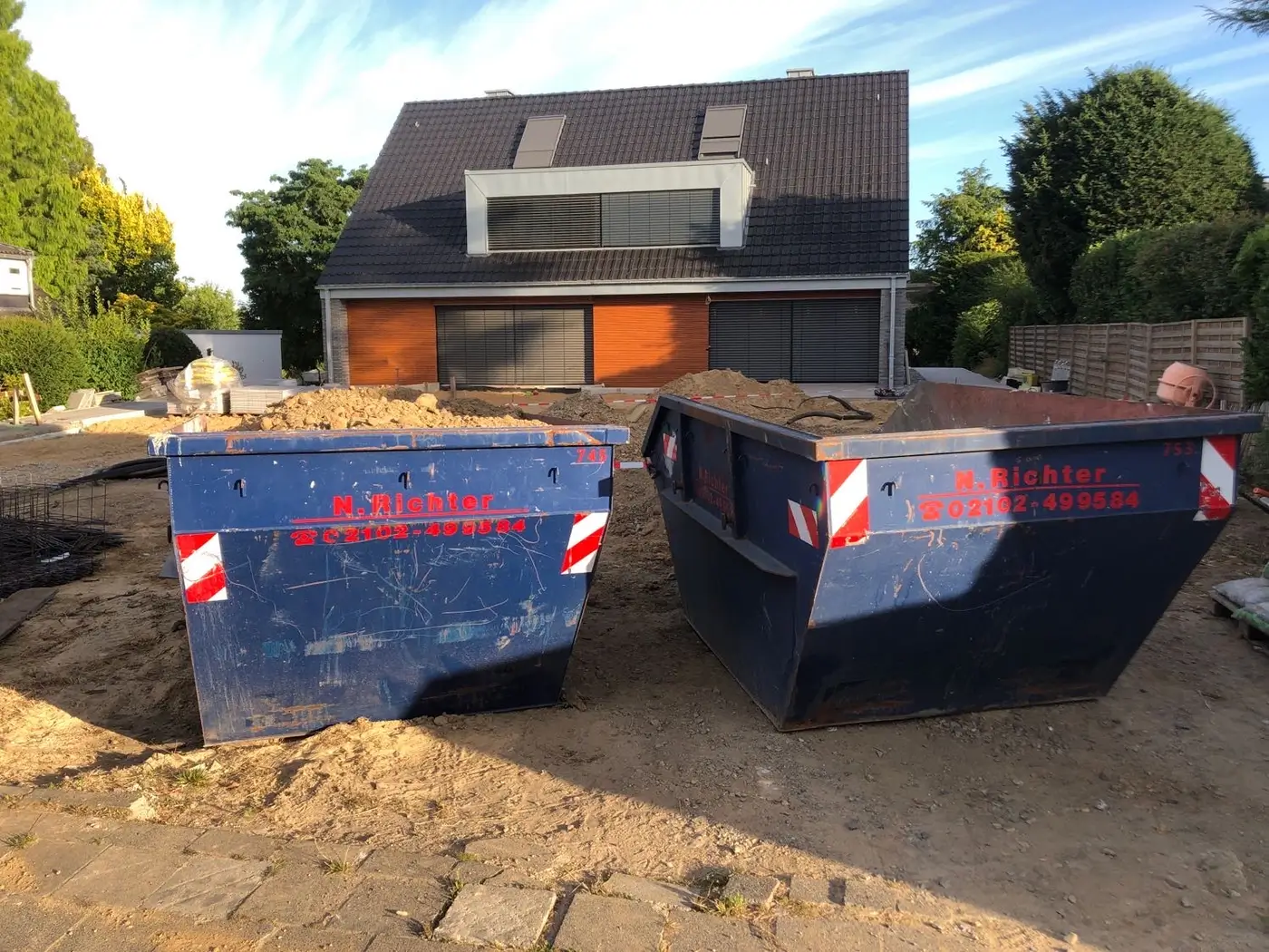 Zwei Container stehen auf einer Baustelle in einem Garten