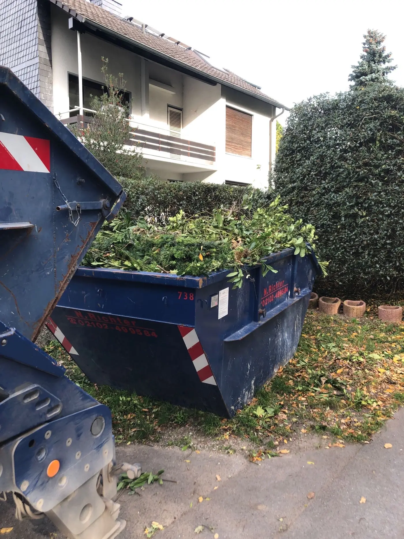 Ein Container von Richter Container in der Einfahrt beim Kunden gefüllt mit Grünschnitt