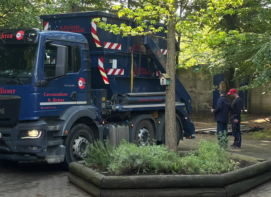 Zwei Mitarbeiter stehen neben einem LKW und entladen gerade einen Container